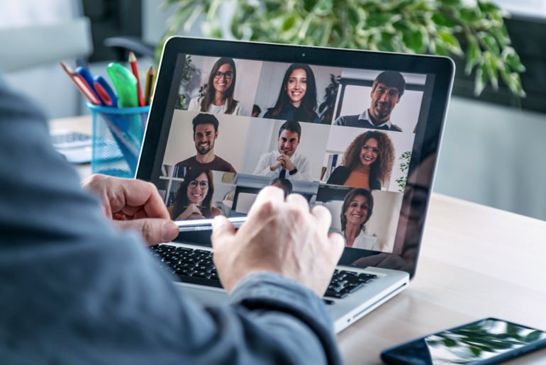 Male employee speaking on video call with diverse colleagues on online briefing with laptop at home.